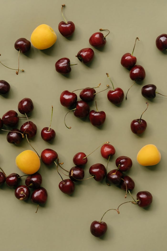 ours-journey Flat lay of ripe cherries and apricots on a green surface, perfect for food themes.